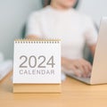 2024 Year Calendar on table with business woman using laptop computer. countdown, Happy New Year, Resolution, Goals, Plan, Action