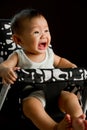 6 month old Asian baby girl crying in high chair Royalty Free Stock Photo