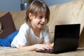 6 year old boy lying on the sofa with his laptop Royalty Free Stock Photo