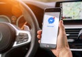 AACHEN, GERMANY AUGUST 2019: Woman holding a Apple iPhone opening Facebook messenger app in a car. Facebook is the world largest