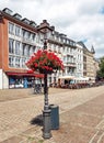 Aachen, Germany - July 31, 2022: A street lamp decorated with pots of red flowers in the central square of Aachen Royalty Free Stock Photo