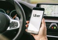 Uber driver holding smartphone in car. Uber is an American company offering different transportation services online