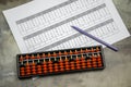 Abacus for mental arithmetic on background of sheet of paper with examples for calculation Royalty Free Stock Photo