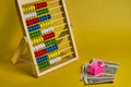 Abacus and shopping basket with dollars at yellow background. Shopping, personal finances, money spendings concept