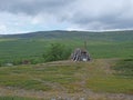 Abadoned Sami hut Goathi in green hills landscape of Abisko National Park. Goahti is Lappish traditional dwelling made from fabric