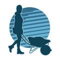 silhouette of a female construction worker pushing a wheelbarrow Royalty Free Stock Photo