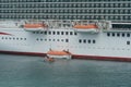 Abandon ship drill with orange life boat and rescue boat of cruiser passenger vessel with white hull. Royalty Free Stock Photo