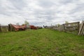 Abandoned agricultural machinery stands near old wooden fences