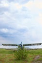 Abandoned aircraft plane standing in the field against cloudy blue sky. Small propeller plane at the airplane cemetery. Royalty Free Stock Photo
