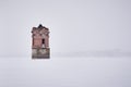 Abandoned ancient water tower in the middle of a frozen river during a snowfall Royalty Free Stock Photo