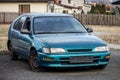 Abandoned azure blue japanese hatchback car with a flat tire