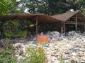 Abandoned bamboo hut with thatched roof made of palm leaves and plastic junk or trash scattered around. Royalty Free Stock Photo
