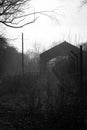 Abandoned barn with a damaged fence in black and white