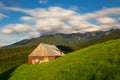 Abandoned barn house in green field with floating clouds in the sky