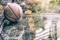 Abandoned basketball on a outdoor field with rain and puddles