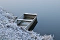 Boat moored by the river bank in winter. Calm blue river, morning frost.