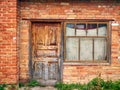 abandoned brick building, shabby old door closed, window curtained with faded fabric Royalty Free Stock Photo