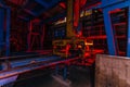 Abandoned brick factory at night. Old rusty brick forming machine and conveyor illuminated by color light. Royalty Free Stock Photo