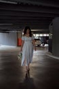 Abandoned bride. Girl in white dress and bouquet in her hand dejectedly wanders through multi-level parking lot in semi Royalty Free Stock Photo