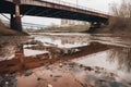 Abandoned bridge over the river with puddles and mud