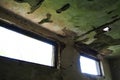 Abandoned building interior. A shabby desolate room with empty broken windows, mold, dust and cobwebs on the walls. The