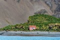 Abandoned building on the shore in Jason Harbor, fur seals on the beach and native landscape in the background, South Georgia, Ant