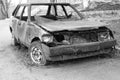 Abandoned burned passenger car near the apartment building. Russia. Monochrome image