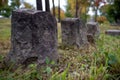 Three dark old grave stones in row with chiseled sides grass cemetery Royalty Free Stock Photo