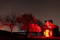 Abandoned church with red light inside and blooming trees nearby nightscape