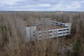 An abandoned concrete building among the trees in Pripyat. Aerial view. Cloudy weather, landscape