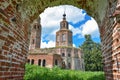 An abandoned dilapidated church, overgrown with grass against the sky, surrounded by greenery, view through the arch