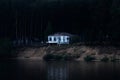 Abandoned dilapidated house on a dark wooded bank almost collapsed into the river Royalty Free Stock Photo