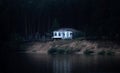 Abandoned dilapidated house on a dark wooded bank almost collapsed into the river