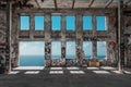 Abandoned factory ruin / warehouse loft with windows and ocean and blue sky background