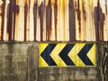 Abandoned factory walls and rusted, weathered tin with yellow and black arrow signs.