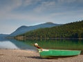 Abandoned fishing paddle boat on bank of Alps lake. Morning lake glowing by sunlight. Royalty Free Stock Photo