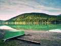 Abandoned fishing paddle boat on bank of Alps lake. Morning lake glowing by sunlight. Royalty Free Stock Photo