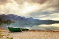 Abandoned fishing paddle boat on bank. Morning Alps lake Royalty Free Stock Photo