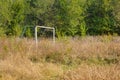 Abandoned football field with iron football goals, overgrown with grass