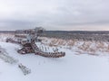 abandoned giant bucket wheel excavator stands in a field in winter