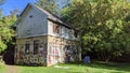 Abandoned graffitied house near green trees on a sunny day