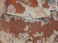 Old peeling red terracotta pink plaster on a cracked rough, scratched uneven concrete stone wall. Royalty Free Stock Photo