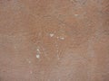 Old peeling red terracotta pink plaster on a cracked rough, scratched uneven concrete stone wall. Royalty Free Stock Photo