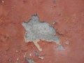 Old peeling red terracotta pink plaster on a cracked rough, scratched uneven concrete stone wall. Royalty Free Stock Photo