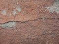 Old peeling red terracotta pink plaster on a cracked rough, scratched uneven concrete stone wall. Royalty Free Stock Photo