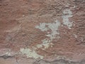 Old peeling red terracotta pink plaster on a cracked rough, scratched uneven concrete stone wall. Royalty Free Stock Photo