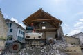 Abandoned house being demolished with mobile walking excavator and rubble and rocks