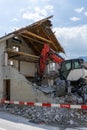 Abandoned house being demolished with mobile walking excavator and rubble and rocks