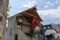 Abandoned house being demolished with mobile walking excavator and rubble and rocks