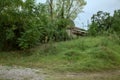 Abandoned house in the countryside hidden behind trees and bushes on a cloudy day Royalty Free Stock Photo